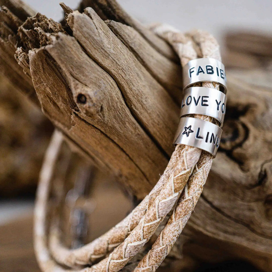 Ein geflochtenes Armband für Herren aus weiß beige Leder im Wickelarmband Look, personalisiert mit Namen Gravur auf Sterling Silber 925 Perlen. Das Armband lässt sich mit einem Karabiner aus Edelstahl verschließen.