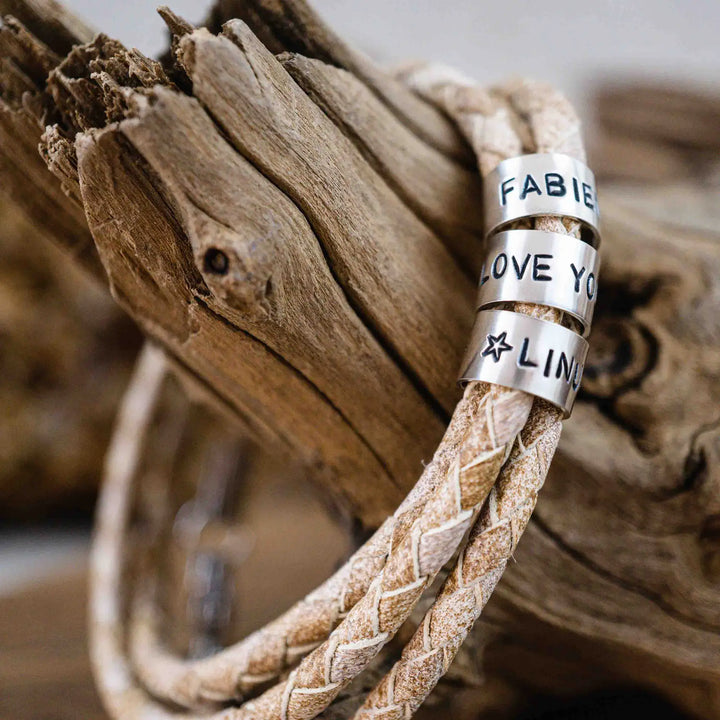 Ein geflochtenes Armband für Herren aus weiß beige Leder im Wickelarmband Look, personalisiert mit Namen Gravur auf Sterling Silber 925 Perlen. Das Armband lässt sich mit einem Karabiner aus Edelstahl verschließen.