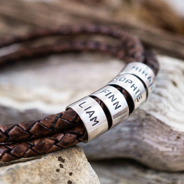 Ein geflochtenes Armband aus braunem Leder im Wickelarmband Look, personalisiert mit Namen Gravur auf Sterling Silber 925 Perlen. Das Armband lässt sich mit einem Karabiner aus Edelstahl verschließen.