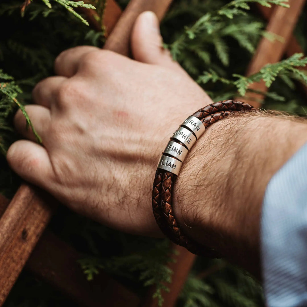 Ein geflochtenes Armband aus braunem Leder im Wickelarmband Look, personalisiert mit Namen Gravur auf Sterling Silber 925 Perlen. Das Armband lässt sich mit einem Karabiner aus Edelstahl verschließen.