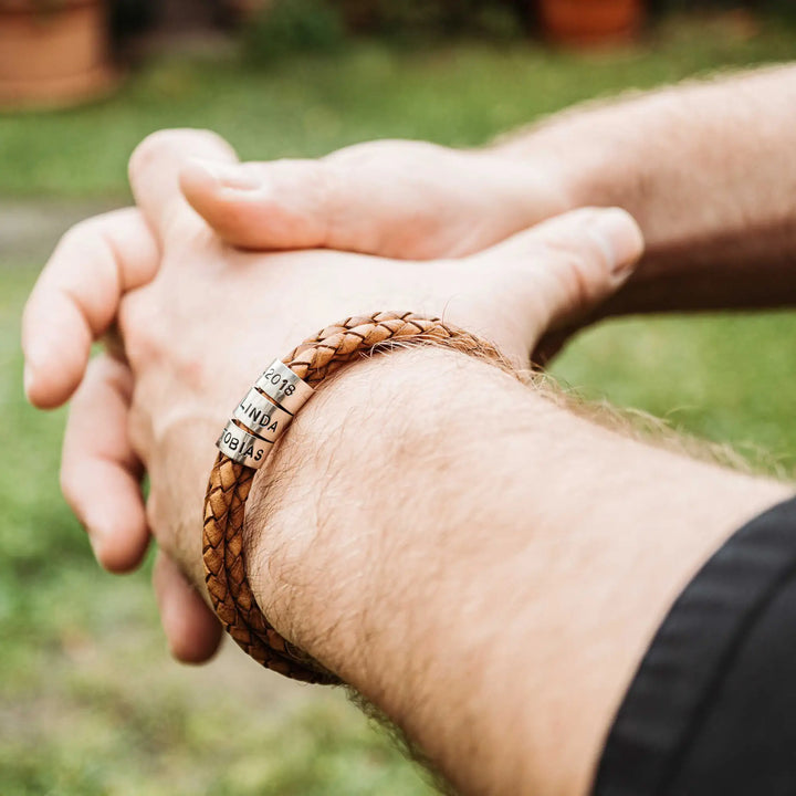 Ein geflochtenes Armband aus hellem braunem Leder im Wickelarmband Look, personalisiert mit Namen Gravur auf Sterling Silber 925 Perlen. Das Armband lässt sich mit einem Karabiner aus Edelstahl verschließen.