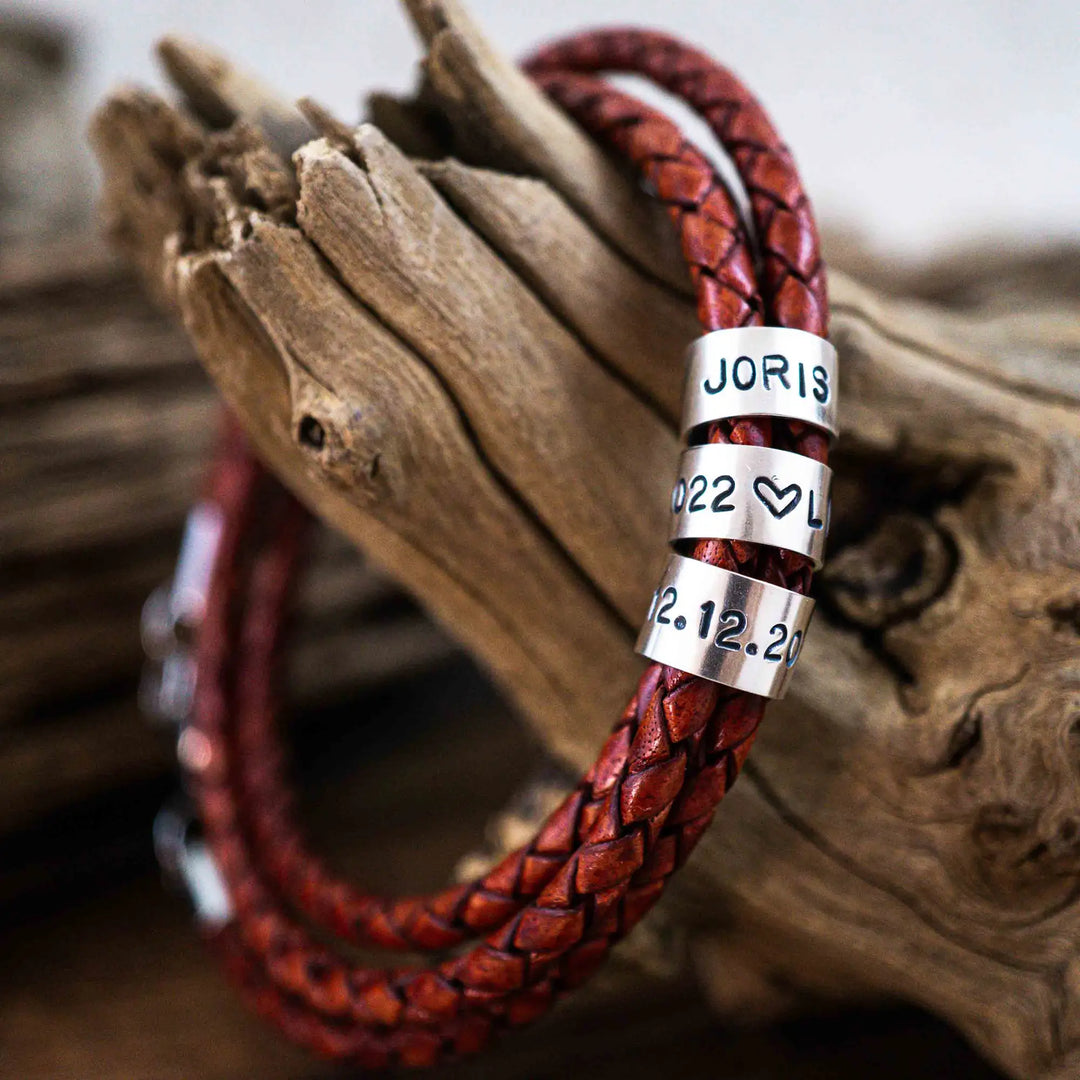 Ein geflochtenes Armband für Herren aus rotem Leder im Wickelarmband Look, personalisiert mit Gravur von Namen und Datum auf Sterling Silber 925 Perlen. Das Armband lässt sich mit einem Karabiner aus Edelstahl verschließen.