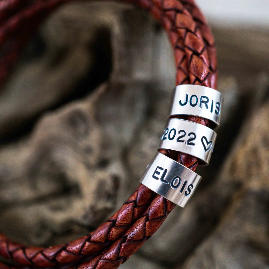 Ein geflochtenes Armband für Herren aus rotem Leder im Wickelarmband Look, personalisiert mit Gravur von Namen und Datum auf Sterling Silber 925 Perlen. Das Armband lässt sich mit einem Karabiner aus Edelstahl verschließen.