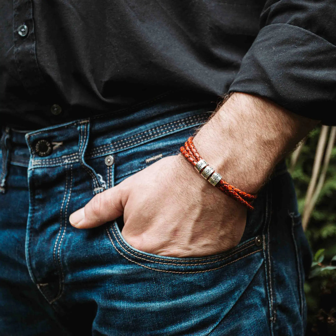 Ein geflochtenes Armband für Herren aus rotem Leder im Wickelarmband Look, personalisiert mit Gravur von Namen und Datum auf Sterling Silber 925 Perlen. Das Armband lässt sich mit einem Karabiner aus Edelstahl verschließen.