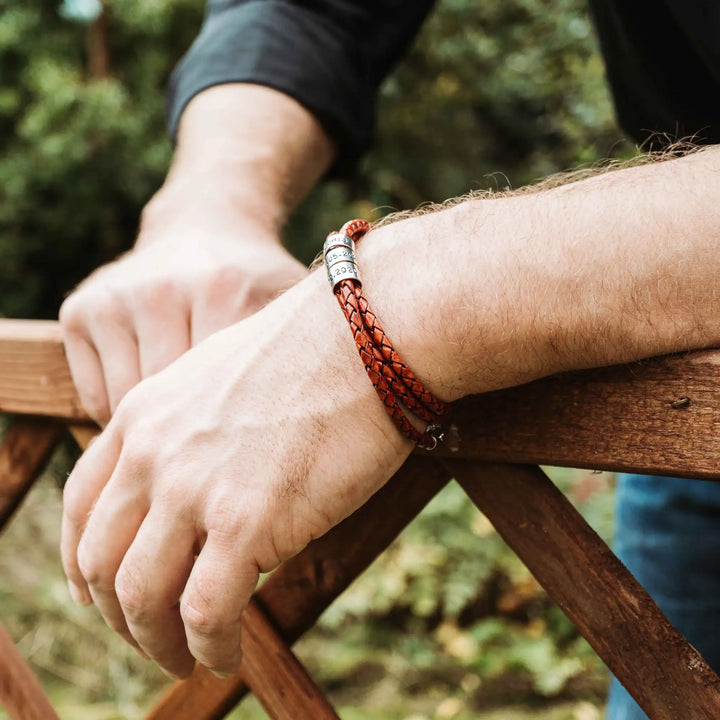 Ein geflochtenes Armband für Herren aus rotem Leder im Wickelarmband Look, personalisiert mit Gravur von Namen und Datum auf Sterling Silber 925 Perlen. Das Armband lässt sich mit einem Karabiner aus Edelstahl verschließen.