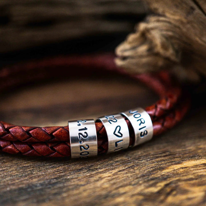 Ein geflochtenes Armband für Herren aus rotem Leder im Wickelarmband Look, personalisiert mit Gravur von Namen und Datum auf Sterling Silber 925 Perlen. Das Armband lässt sich mit einem Karabiner aus Edelstahl verschließen.