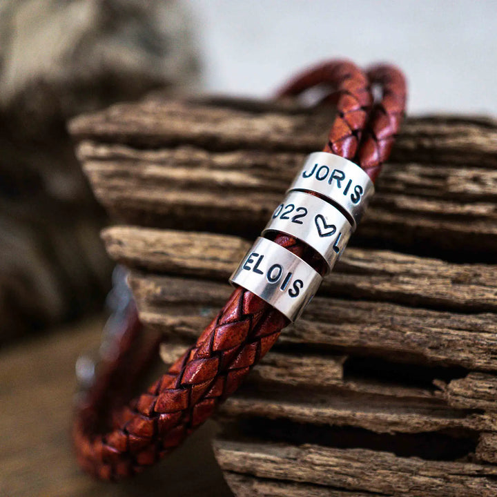 Ein geflochtenes Armband für Herren aus rotem Leder im Wickelarmband Look, personalisiert mit Gravur von Namen und Datum auf Sterling Silber 925 Perlen. Das Armband lässt sich mit einem Karabiner aus Edelstahl verschließen.
