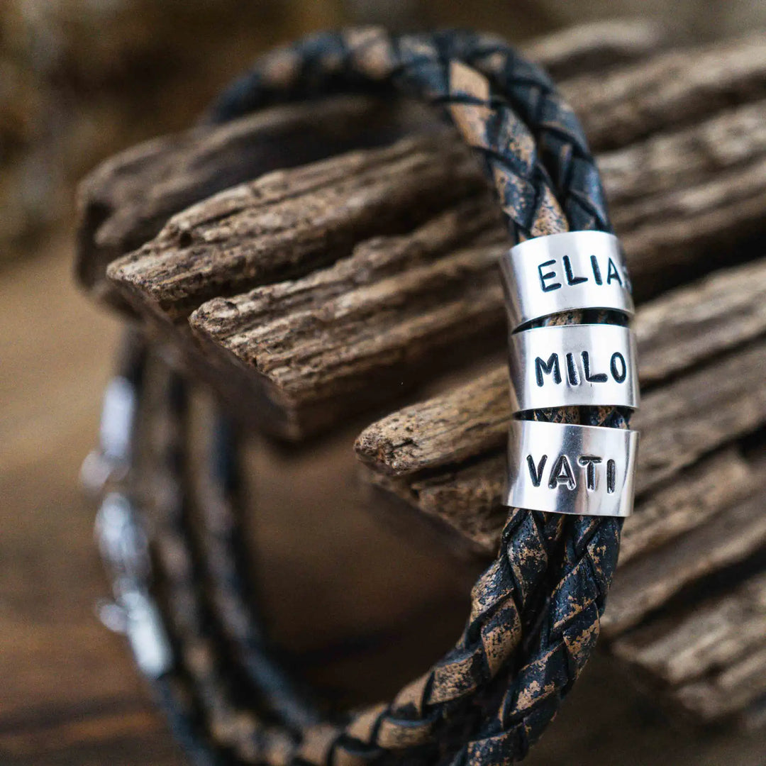 Ein geflochtenes Armband für Herren aus rustikalem, braun-schwarzen Leder im Wickelarmband Look, personalisiert mit Namen Gravur auf Sterling Silber 925 Perlen. Das Armband lässt sich mit einem Karabiner aus Edelstahl verschließen.