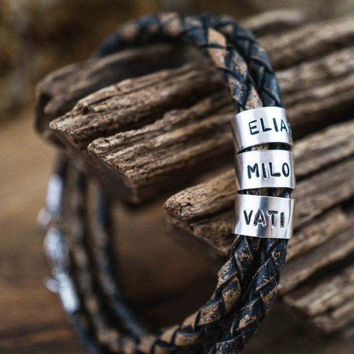 Ein geflochtenes Armband für Herren aus rustikalem, braun-schwarzen Leder im Wickelarmband Look, personalisiert mit Namen Gravur auf Sterling Silber 925 Perlen. Das Armband lässt sich mit einem Karabiner aus Edelstahl verschließen.