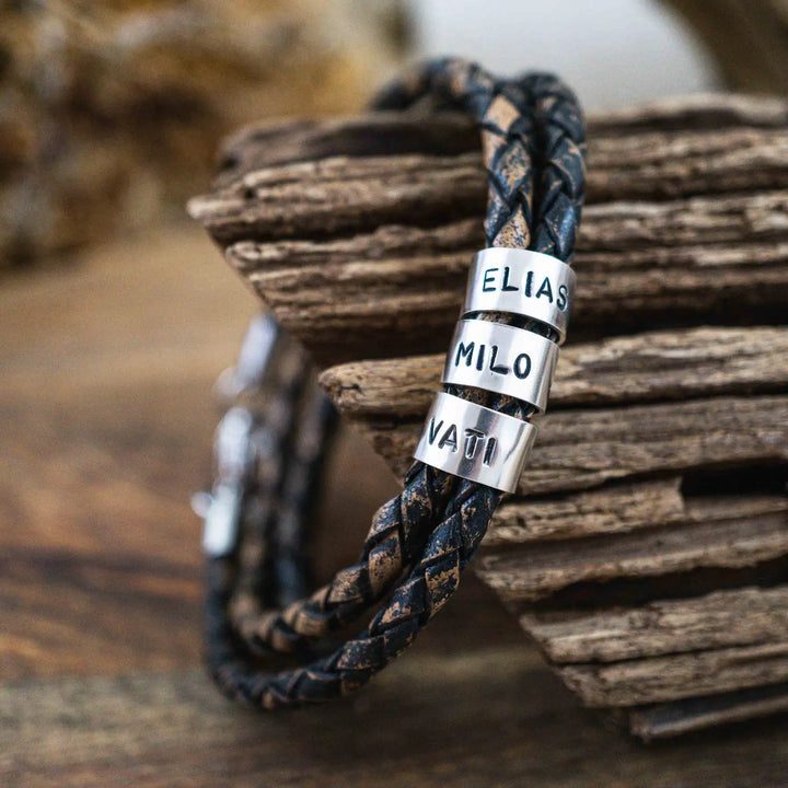 Ein geflochtenes Armband für Herren aus rustikalem, braun-schwarzen Leder im Wickelarmband Look, personalisiert mit Namen Gravur auf Sterling Silber 925 Perlen. Das Armband lässt sich mit einem Karabiner aus Edelstahl verschließen.