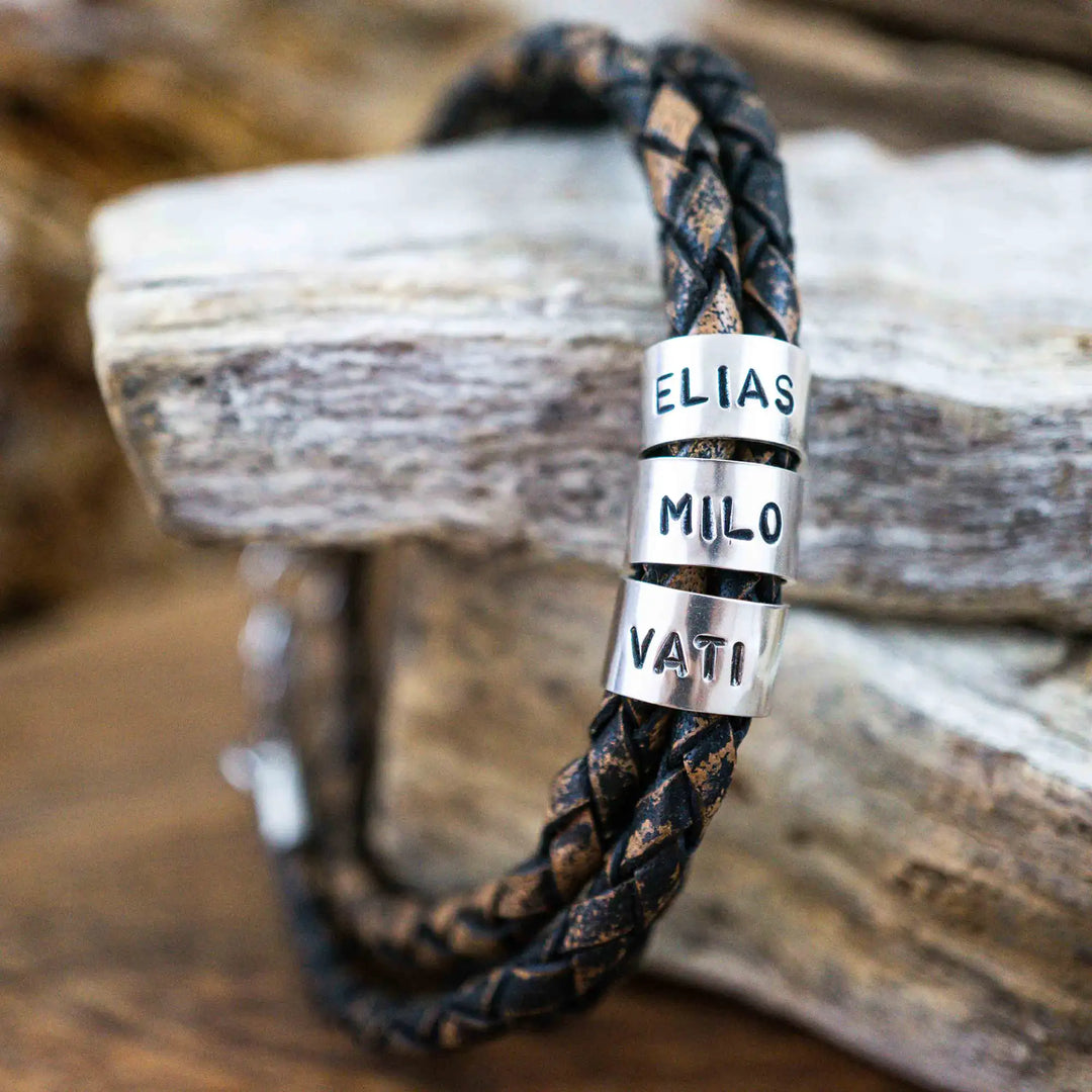 Ein geflochtenes Armband für Herren aus rustikalem, braun-schwarzen Leder im Wickelarmband Look, personalisiert mit Namen Gravur auf Sterling Silber 925 Perlen. Das Armband lässt sich mit einem Karabiner aus Edelstahl verschließen.