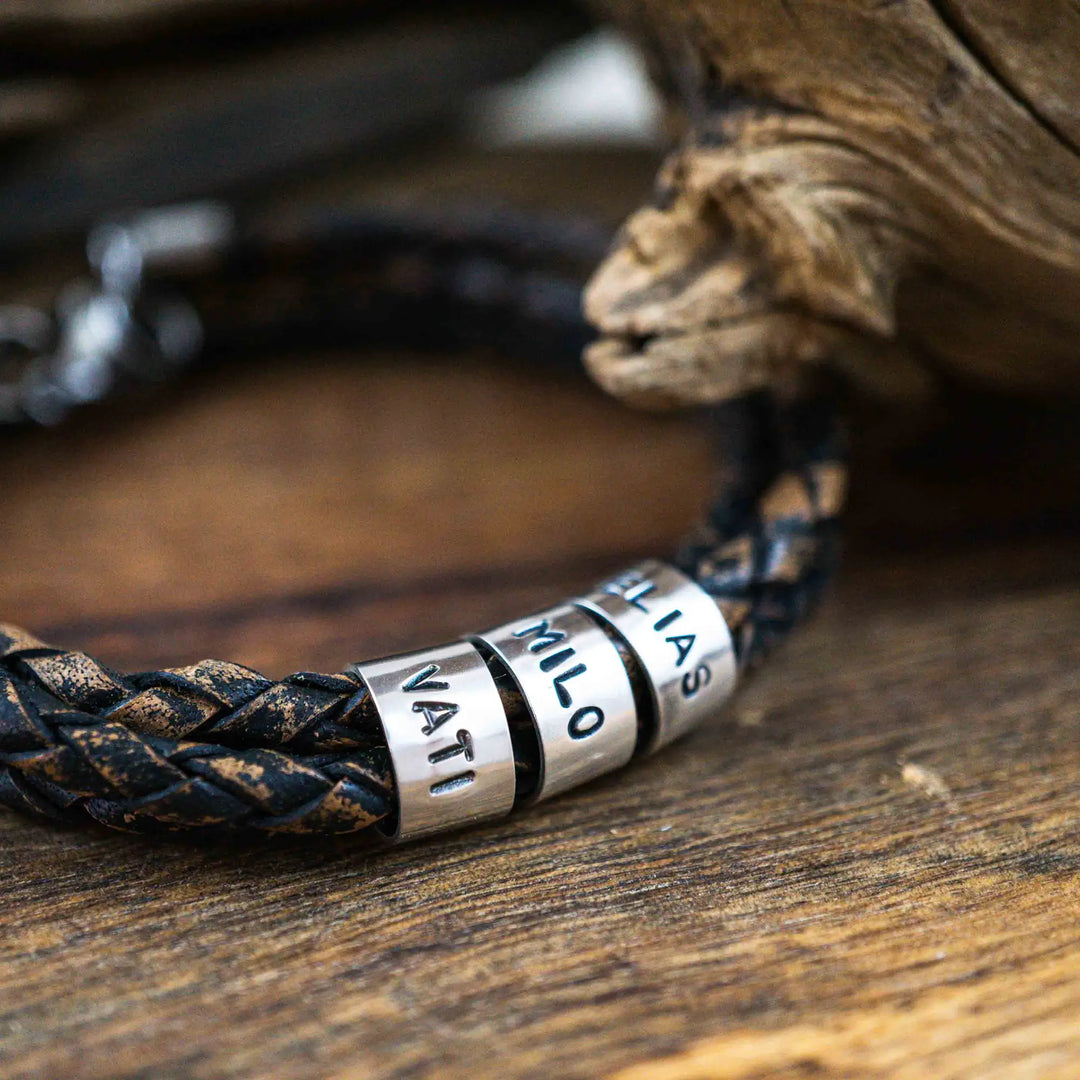 Ein geflochtenes Armband für Herren aus rustikalem, braun-schwarzen Leder im Wickelarmband Look, personalisiert mit Namen Gravur auf Sterling Silber 925 Perlen. Das Armband lässt sich mit einem Karabiner aus Edelstahl verschließen.