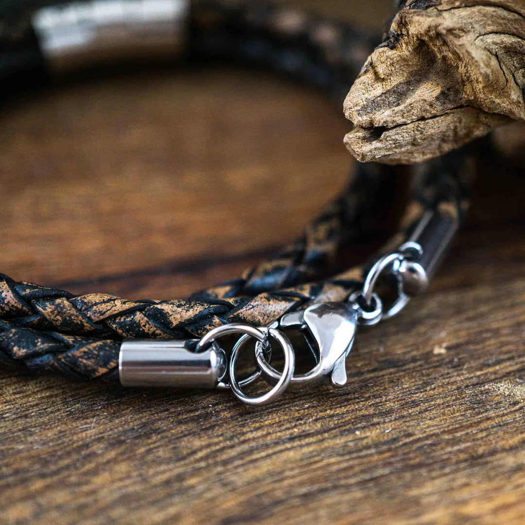 Ein geflochtenes Armband für Herren aus rustikalem, braun-schwarzen Leder im Wickelarmband Look, personalisiert mit Namen Gravur auf Sterling Silber 925 Perlen. Das Armband lässt sich mit einem Karabiner aus Edelstahl verschließen.