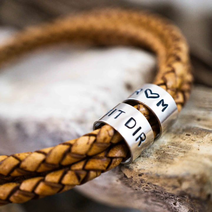 Ein geflochtenes Armband für Herren aus senfgelbem/hellbraunem Leder im Wickelarmband Look, personalisiert mit Namen und Datum Gravur auf Sterling Silber 925 Perlen. Das Armband lässt sich mit einem Karabiner aus Edelstahl verschließen.
