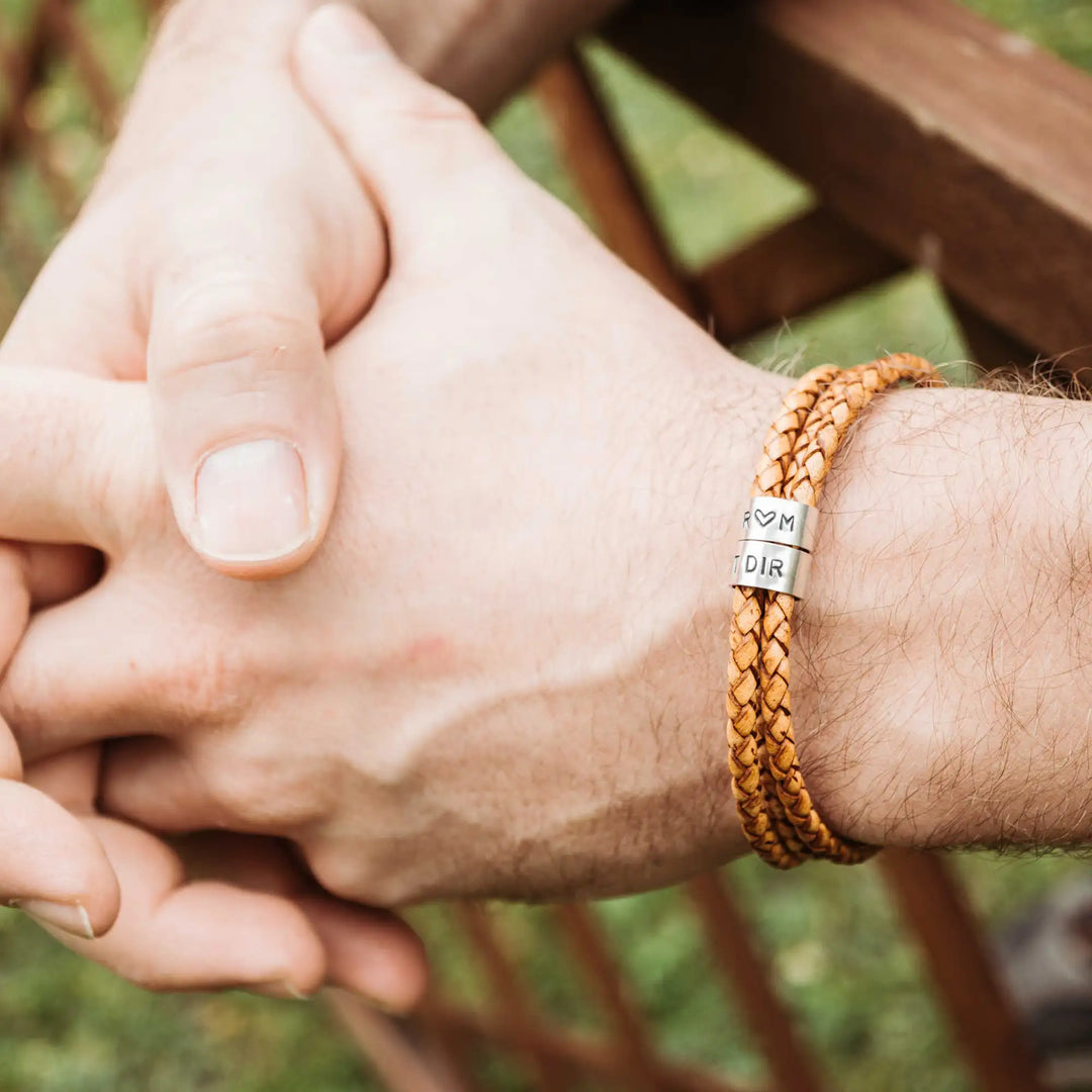 Ein geflochtenes Armband für Herren aus senfgelbem/hellbraunem Leder im Wickelarmband Look, personalisiert mit Namen und Datum Gravur auf Sterling Silber 925 Perlen. Das Armband lässt sich mit einem Karabiner aus Edelstahl verschließen.