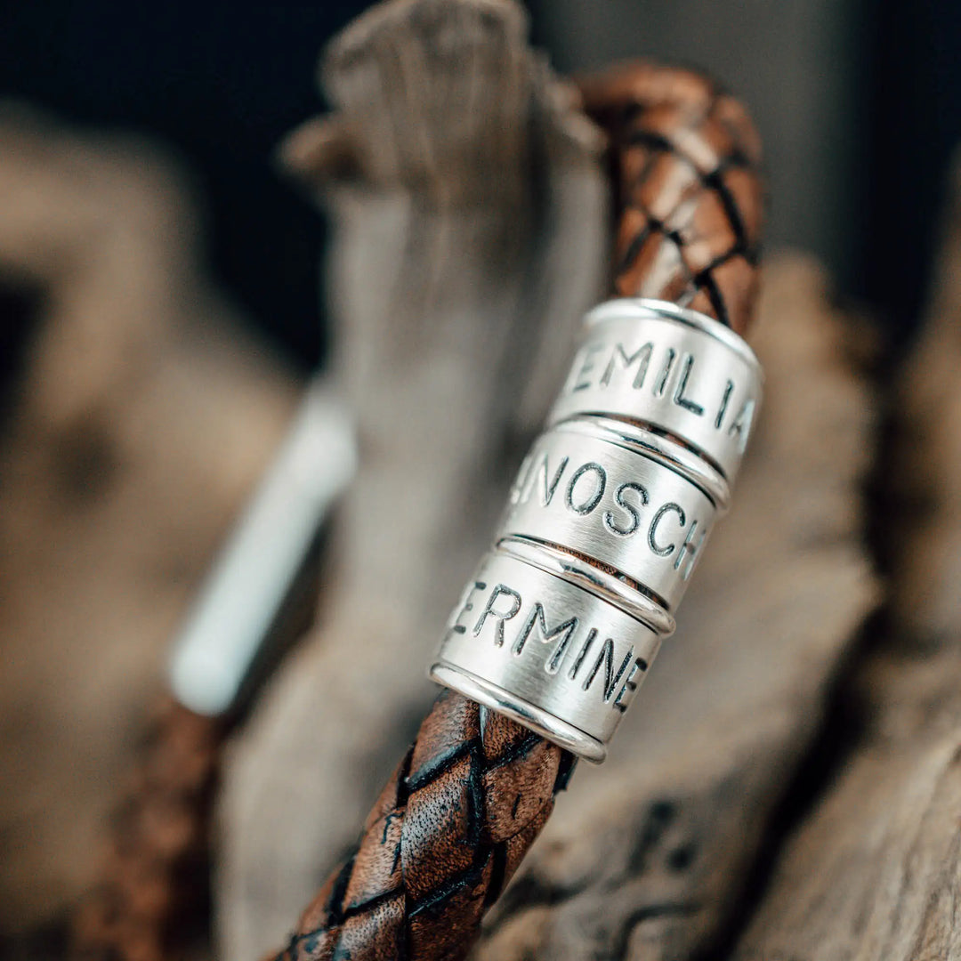 Ein dickes, geflochtenes Armband für Herren aus braunem Leder, personalisiert mit Gravur von Namen und Datum auf Sterling Silber 925 Perlen. Das Armband lässt sich mit einem stabilen Verschluss aus Edelstahl verschließen.