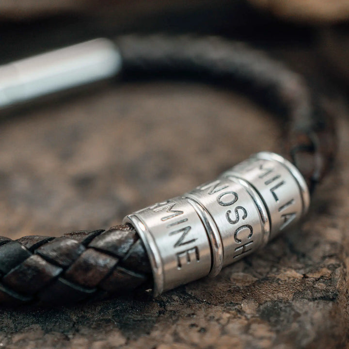 Ein dickes, geflochtenes Armband für Herren aus braunem dunklen Leder, personalisiert mit Gravur von Namen und Datum auf Sterling Silber 925 Perlen. Das Armband lässt sich mit einem stabilen Verschluss aus Edelstahl verschließen.