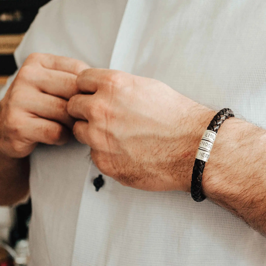 Ein dickes, geflochtenes Armband für Herren aus braunem dunklen Leder, personalisiert mit Gravur von Namen und Datum auf Sterling Silber 925 Perlen. Das Armband lässt sich mit einem stabilen Verschluss aus Edelstahl verschließen.