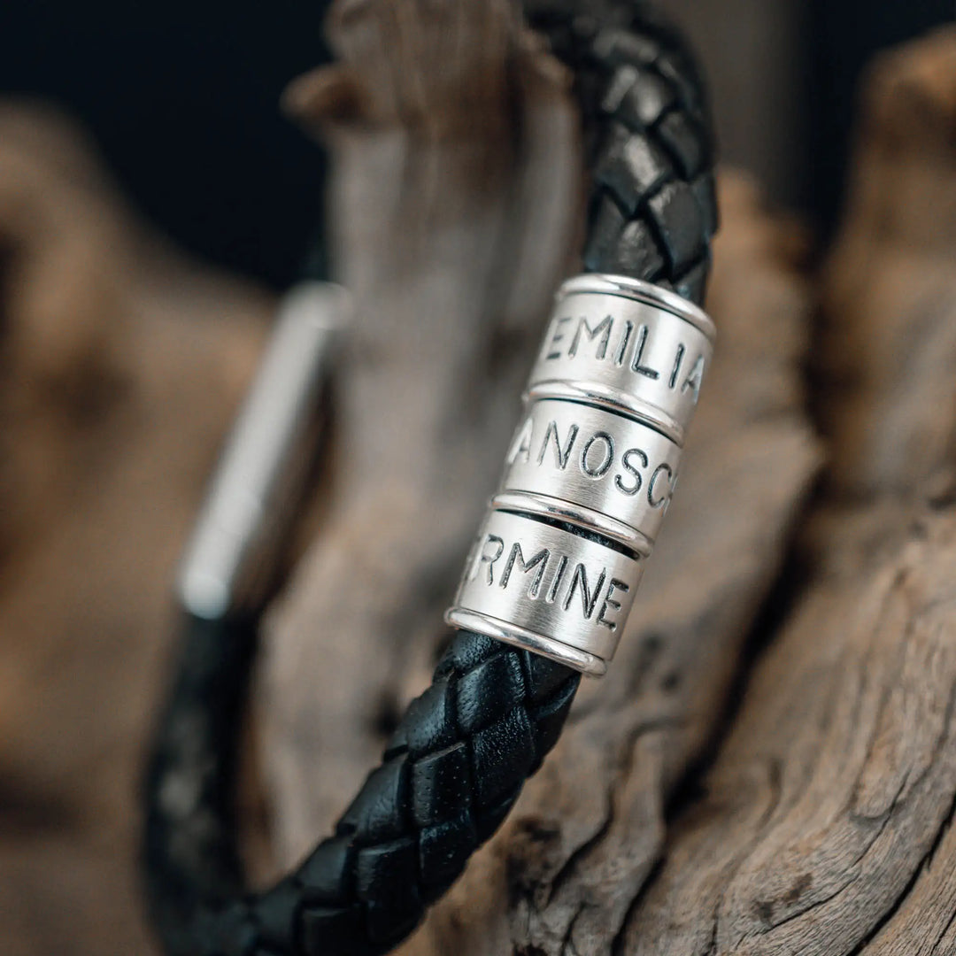 Ein dickes, geflochtenes Armband für Herren aus schwarzem Leder, personalisiert mit Gravur von Namen und Datum auf Sterling Silber 925 Perlen. Das Armband lässt sich mit einem stabilen Verschluss aus Edelstahl verschließen.