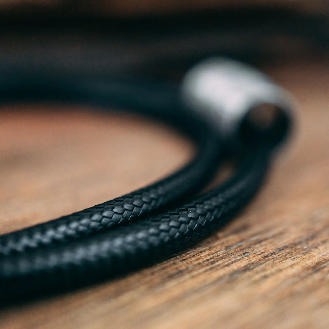 Eine vegane Halskette für Männer aus schwarzem Synthetik/Baumwoll-Band. Die Kette für Herren ist personalisiert mit Gravur von Namen oder Datum auf zylindrischen Sterling Silber 925 Perlen. Das Kette lässt sich mit einem stabilen Karabiner Verschluss aus Edelstahl verschließen.