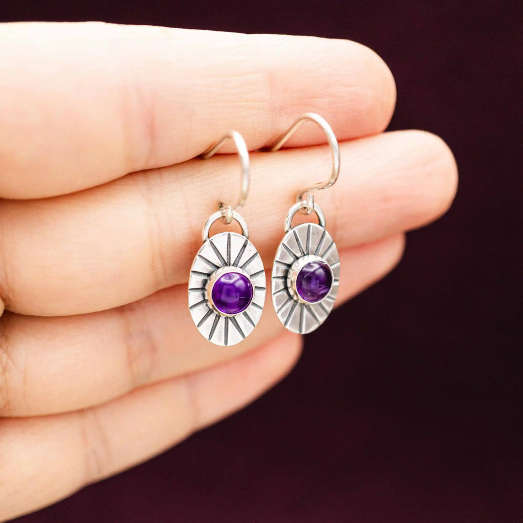 Kleine handgefertigte Ohrringe mit Amethyst auf der Hand fotografiert