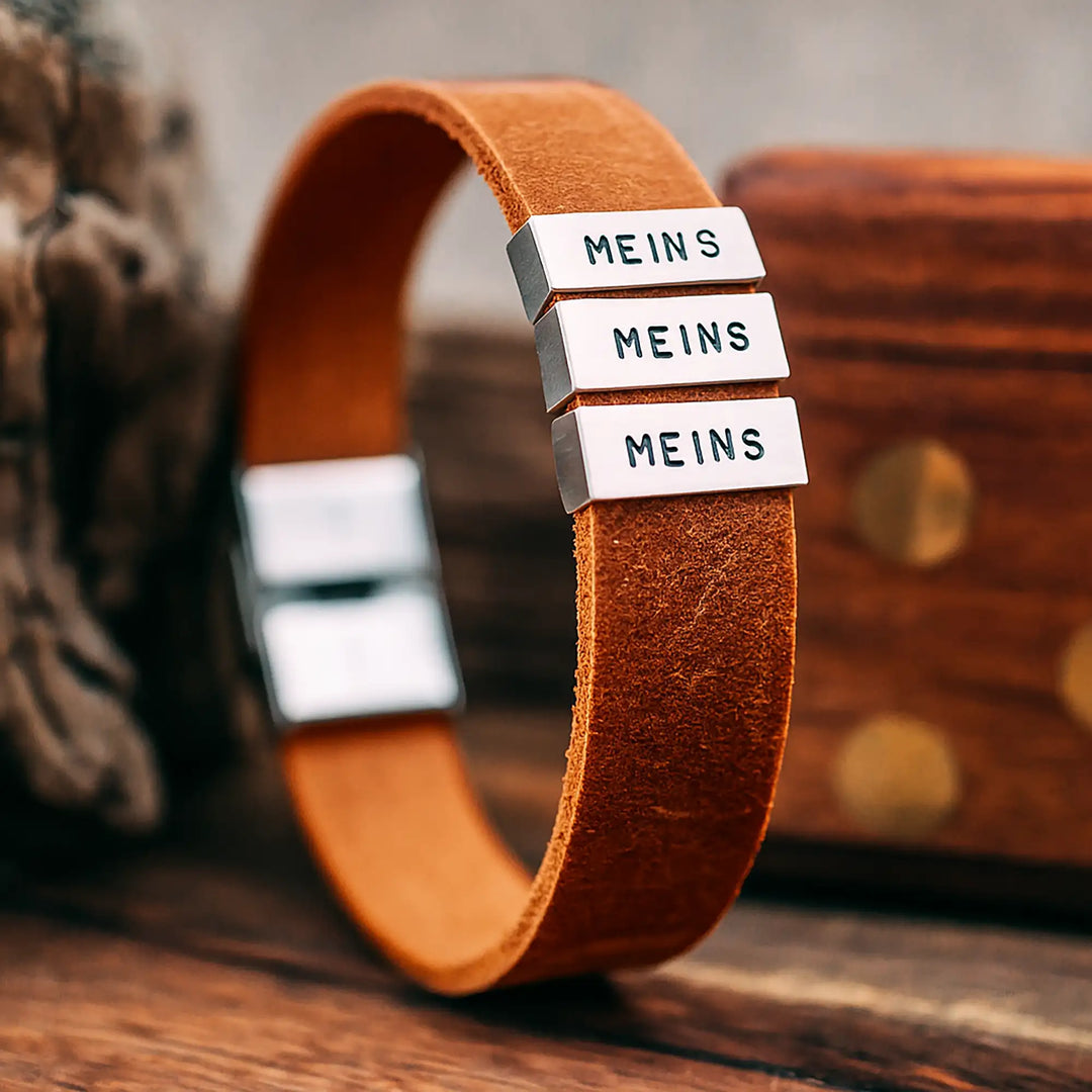 Ein flaches, braunes Armband für Herren aus Nukub Leder, personalisiert mit Gravur von Namen, Koordinaten und Datum auf Sterling Silber 925 Perlen. Das Armband lässt sich mit einem stabilen Verschluss aus Edelstahl verschließen.