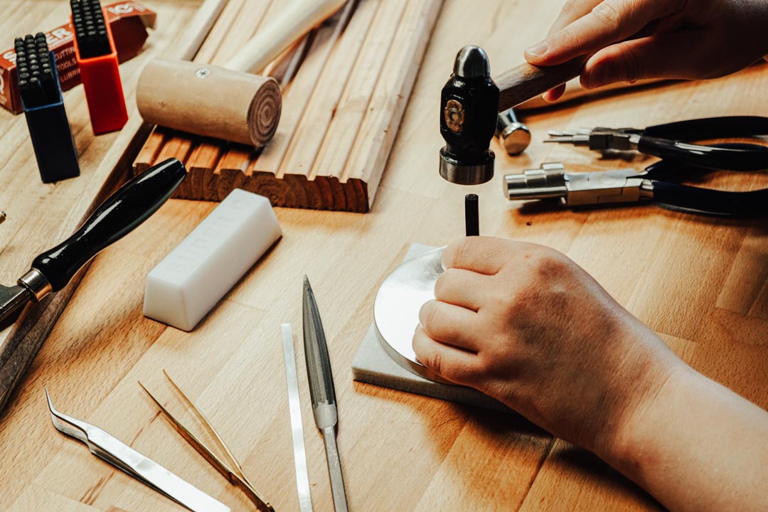 Die Herstellung einer personalisierten Gravur (Punzierung) auf Sterling Silber mit Hammer und Punze für ein Herren Armband.
