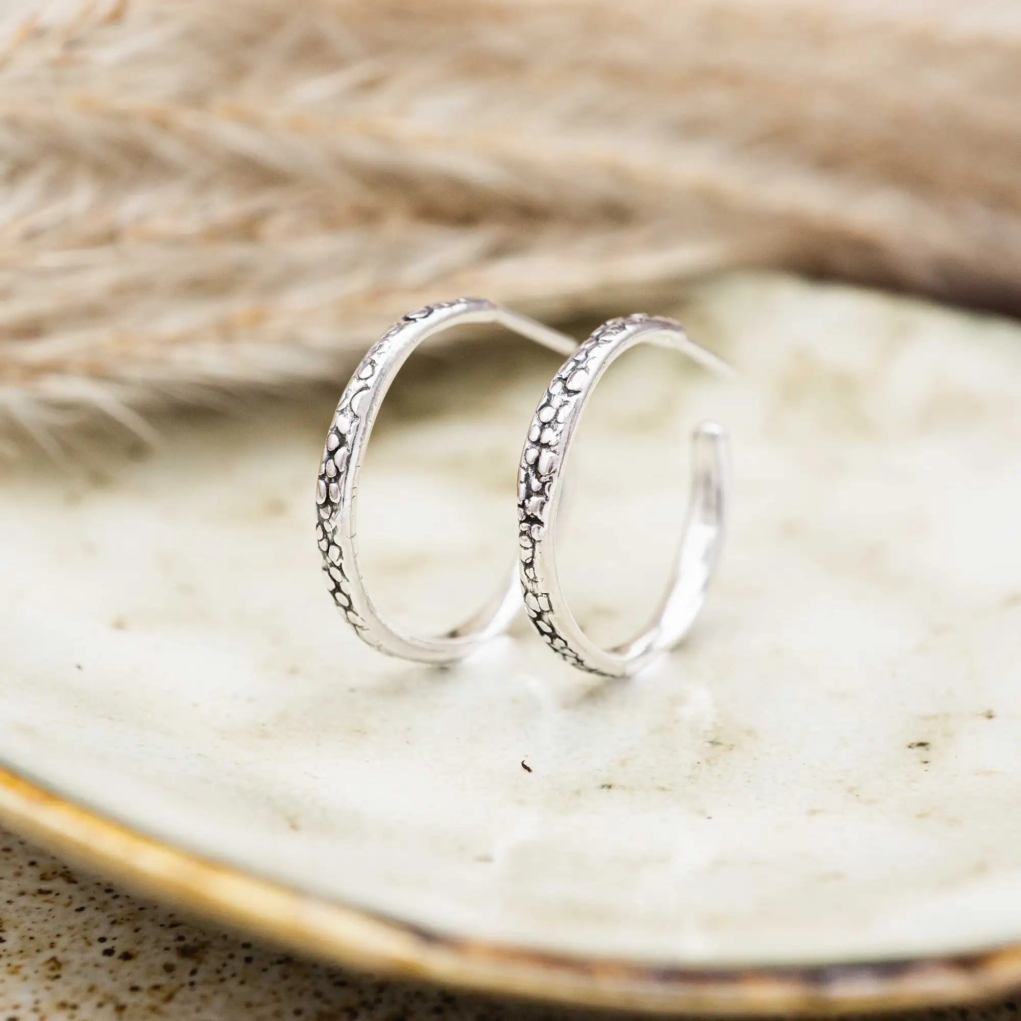 Kleine Creolen aus Silber 925, versehen mit einer organischen, patinierten Textur.