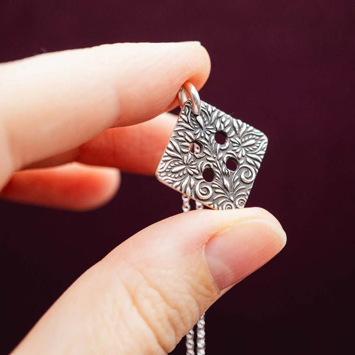 Freundschaftskette aus Silber 925 mit einem Knopf Anhänger an einer Kette. Der Knopf Anhänger ist eckig und mit einem floralen Muster versehen. Der eckige Knopf steht für Zusammenhalt, auch wenn nicht immer alles ganz "rund" läuft.