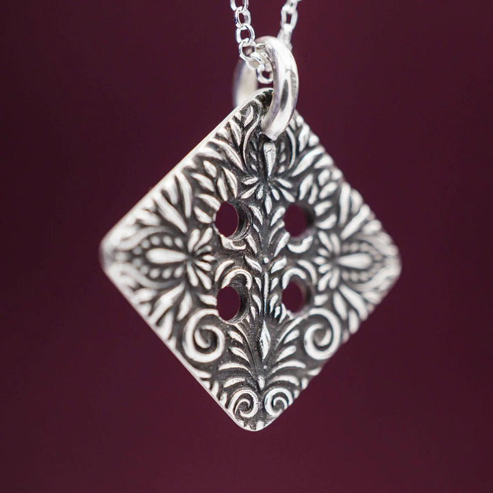 Freundschaftskette aus Silber 925 mit einem Knopf Anhänger an einer Kette. Der Knopf Anhänger ist eckig und mit einem floralen Muster versehen. Der eckige Knopf steht für Zusammenhalt, auch wenn nicht immer alles ganz "rund" läuft.