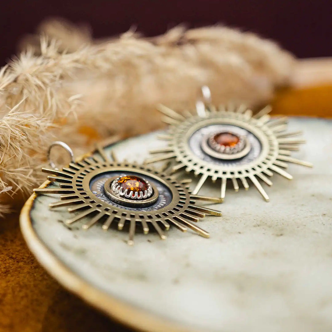 Große goldene Statement Ohrringe in Form einer Sonne mit Sonnenstrahlen. In der Mitte ist ein runder Bernstein in Sterling Silber 925 eingefasst. Die auffälligen und ausgefallenen Statement Ohrringe mit Goddess-Vibes sind handgefertigter Silberschmuck aus der Silberschmiede und bestehen aus Silber und goldenem Messing.