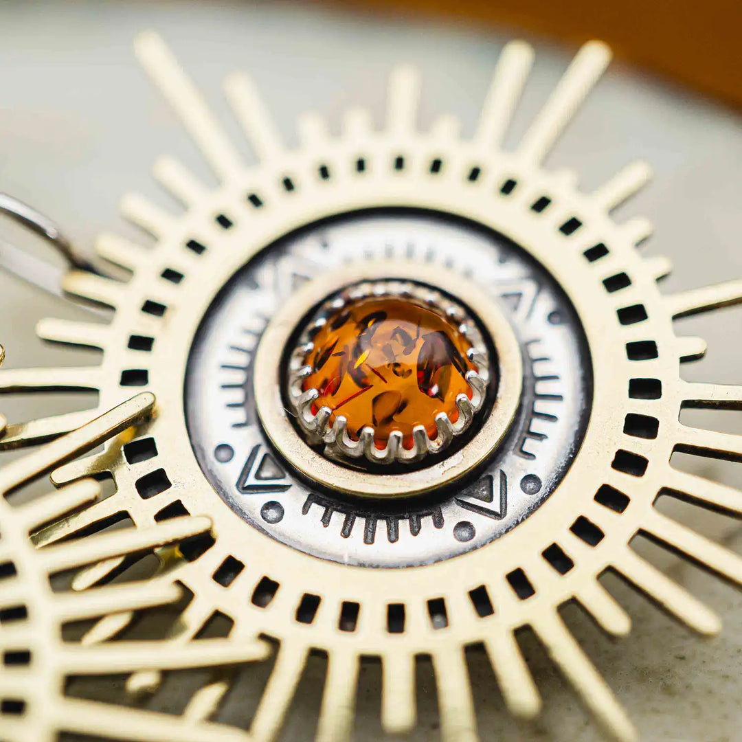 Große goldene Statement Ohrringe in Form einer Sonne mit Sonnenstrahlen. In der Mitte ist ein runder Bernstein in Sterling Silber 925 eingefasst. Die auffälligen und ausgefallenen Statement Ohrringe mit Goddess-Vibes sind handgefertigter Silberschmuck aus der Silberschmiede und bestehen aus Silber und goldenem Messing.