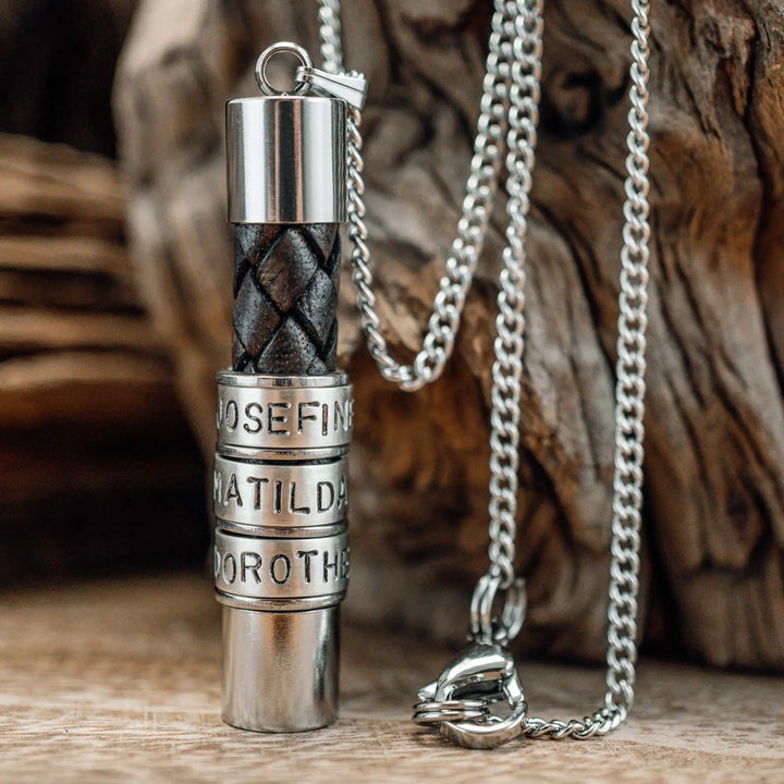 Eine Halskette für Männer aus braunem Leder-Anhänger und einer Edelstahl-Kette. Die Kette für Herren ist an dem zylindrischen Anhänger aus Leder personalisiert mit Gravur von Namen oder Datum auf zylindrischen Sterling Silber 925 Perlen. Die Kette lässt sich mit einem silbernen Karabiner aus Edelstahl verschließen.