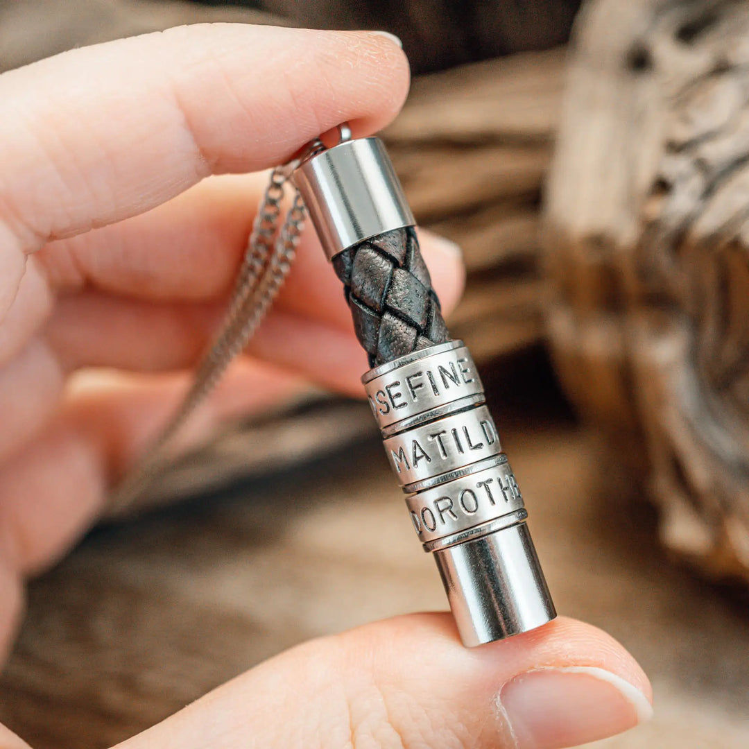 Eine Halskette für Männer aus braunem Leder-Anhänger und einer Edelstahl-Kette. Die Kette für Herren ist an dem zylindrischen Anhänger aus Leder personalisiert mit Gravur von Namen oder Datum auf zylindrischen Sterling Silber 925 Perlen. Die Kette lässt sich mit einem silbernen Karabiner aus Edelstahl verschließen.