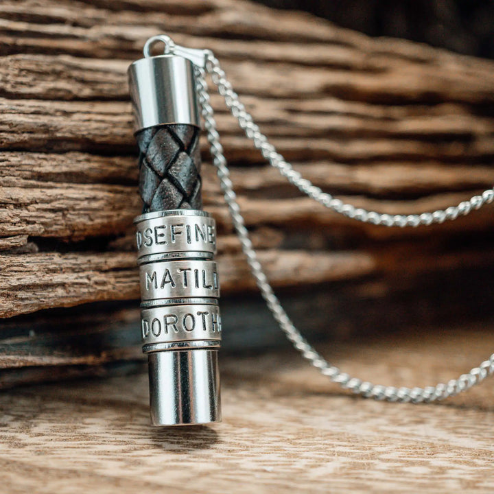 Eine Halskette für Männer aus braunem Leder-Anhänger und einer Edelstahl-Kette. Die Kette für Herren ist an dem zylindrischen Anhänger aus Leder personalisiert mit Gravur von Namen oder Datum auf zylindrischen Sterling Silber 925 Perlen. Die Kette lässt sich mit einem silbernen Karabiner aus Edelstahl verschließen.