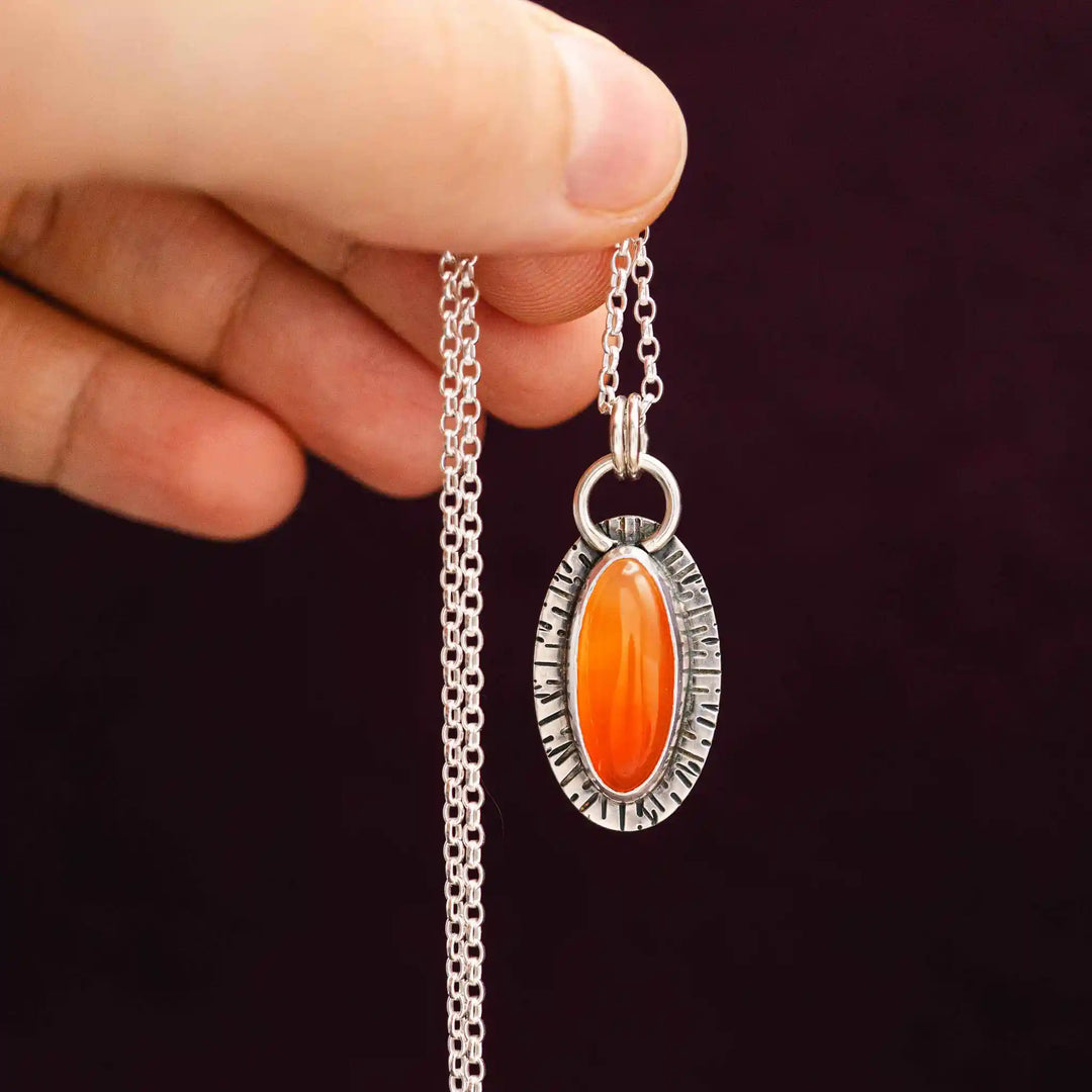 Detailaufnahme einer handgemachten Karneol-Kette mit warm orangefarbenem Edelstein und rustikaler Silberstruktur.