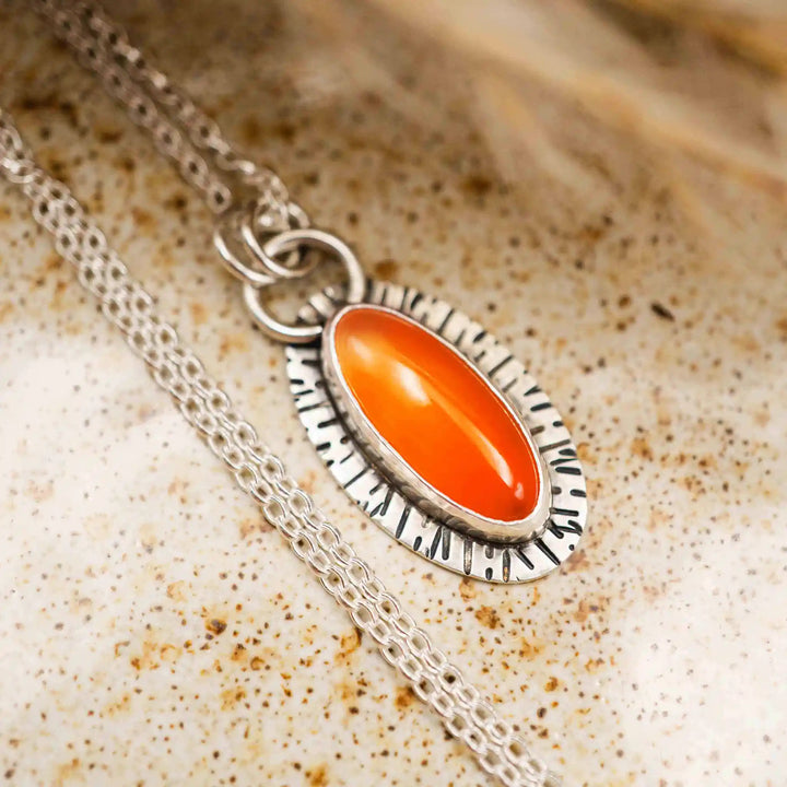 Handgefertigte Karneol-Kette aus Silber 925 mit ovalem orangefarbenem Stein und organischer Sonnenstrahlen-Textur.