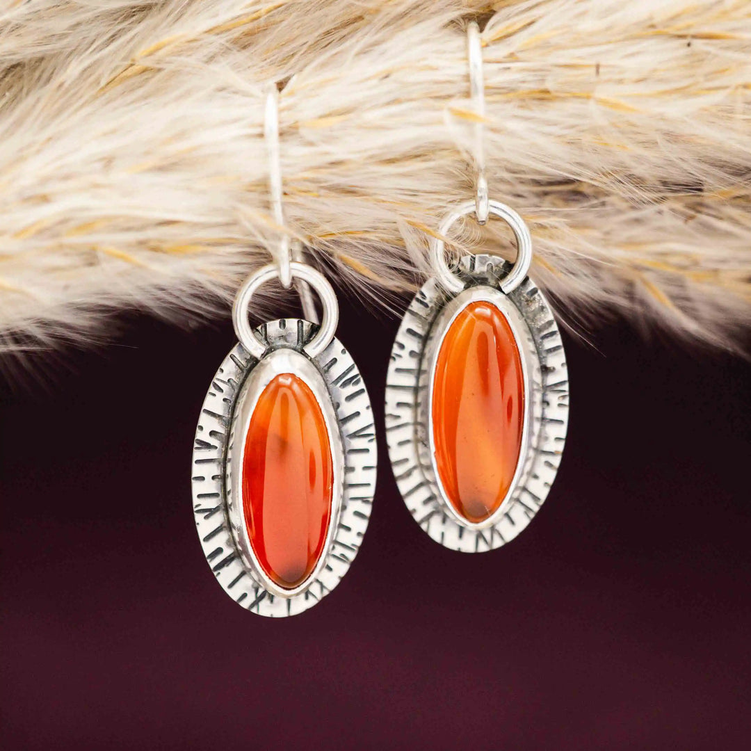 Ovale Ohrhänger aus Sterling Silber 925 mit rot-orange leuchtenden Karneolen auf dunklem Hintergrund