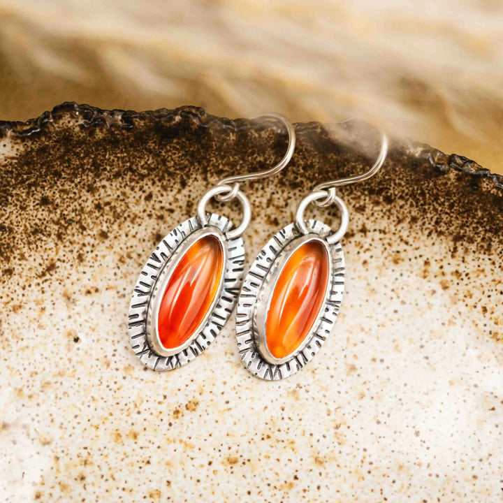 Handgefertigte Karneol Ohrringe aus Silber 925 mit ovalen rot-orangenen Edelsteinen und geprägten Sonnenstrahl-Details