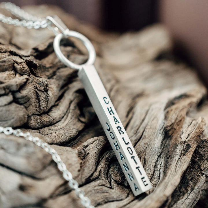 Eine Halskette mit Gravur für Frauen. Sie besteht aus einem Anhänger an einem Ring und einer Kette aus Sterling Silber 925. Die Kette für Damen ist auf dem ca 4cm langen, rechteckigen Anhänger personalisiert mit Gravur von Namen oder Datum auf allen 4 Seiten des Anhängers. Die Kette lässt sich mit einem silbernen Karabiner aus Edelstahl verschließen.