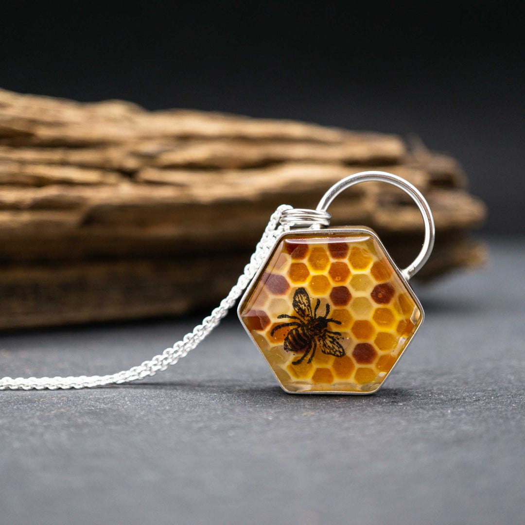 Kette aus Silber mit Honigwaben in gelb und orange mit einer schwarzen Biene. Die von Hand modellierte Honigwabe sitzt in einer silbernen Fassung aus 925 Sterling Silber. Die Rückseite des mittelgroßen Anhängers zieren ins Metall geschlagene Blumen und eine Biene.