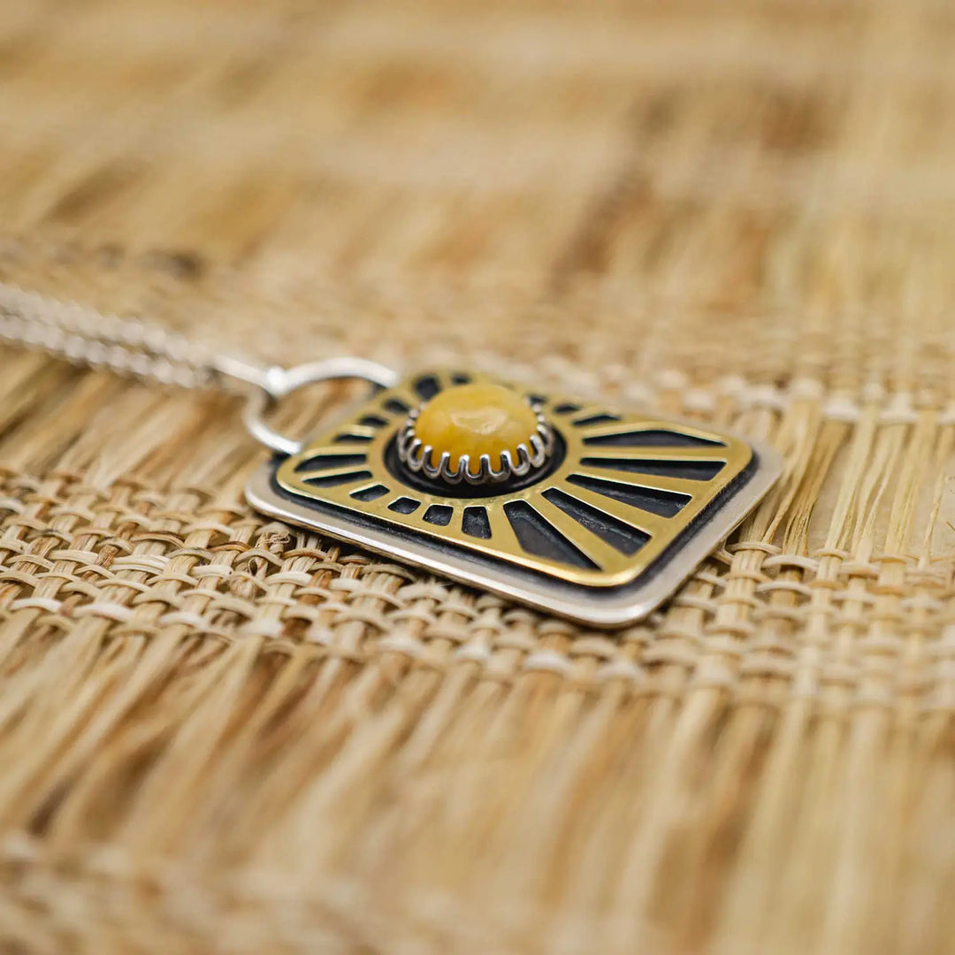 Kette aus Sterling Silber 925 mit gelbem Achat. Die handgefertigte Silberkette ist rechteckig und mit einer goldenen Sonne aus Messing versehen. In der Mitte der Sonne sitzt eingefasst in silberne Spitze, ein gelber Achat (Aventurin).
Auf der Rückseite des handgefertigten Silberschmucks ist zur Motivation eingraviert: "Alles unter der Sonne", um uns auch in schweren Zeiten zu erinnern, wie wertvoll das Leben ist.