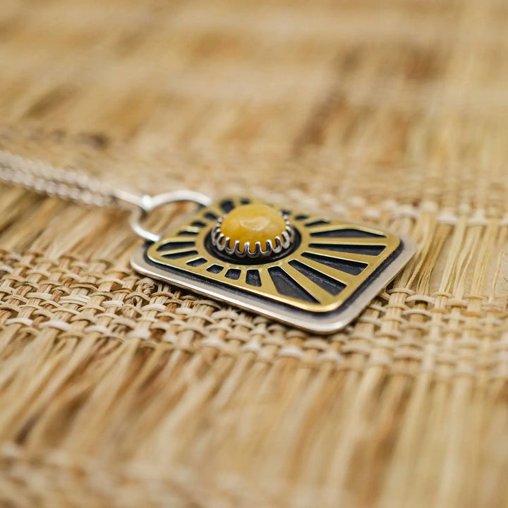 Kette aus Sterling Silber 925 mit gelbem Achat. Die handgefertigte Silberkette ist rechteckig und mit einer goldenen Sonne aus Messing versehen. In der Mitte der Sonne sitzt eingefasst in silberne Spitze, ein gelber Achat (Aventurin).
Auf der Rückseite des handgefertigten Silberschmucks ist zur Motivation eingraviert: "Alles unter der Sonne", um uns auch in schweren Zeiten zu erinnern, wie wertvoll das Leben ist.