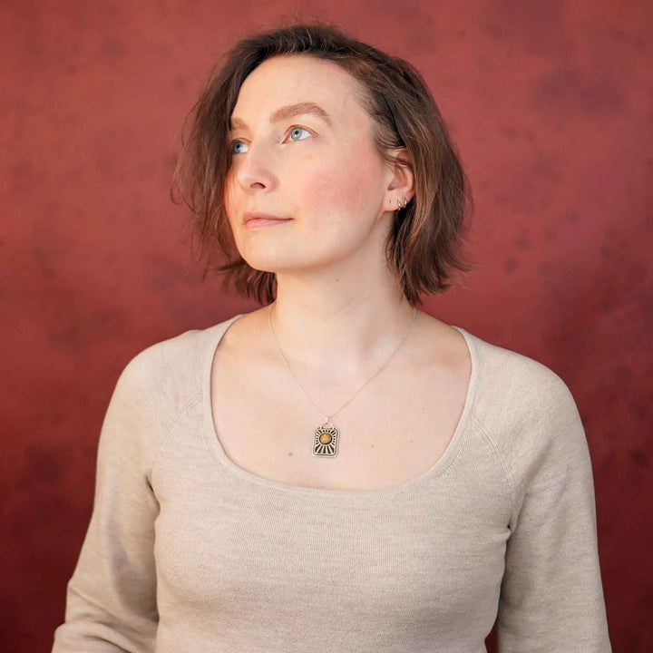 Kette aus Sterling Silber 925 mit gelbem Achat. Die handgefertigte Silberkette ist rechteckig und mit einer goldenen Sonne aus Messing versehen. In der Mitte der Sonne sitzt eingefasst in silberne Spitze, ein gelber Achat (Aventurin).
Auf der Rückseite des handgefertigten Silberschmucks ist zur Motivation eingraviert: "Alles unter der Sonne", um uns auch in schweren Zeiten zu erinnern, wie wertvoll das Leben ist.