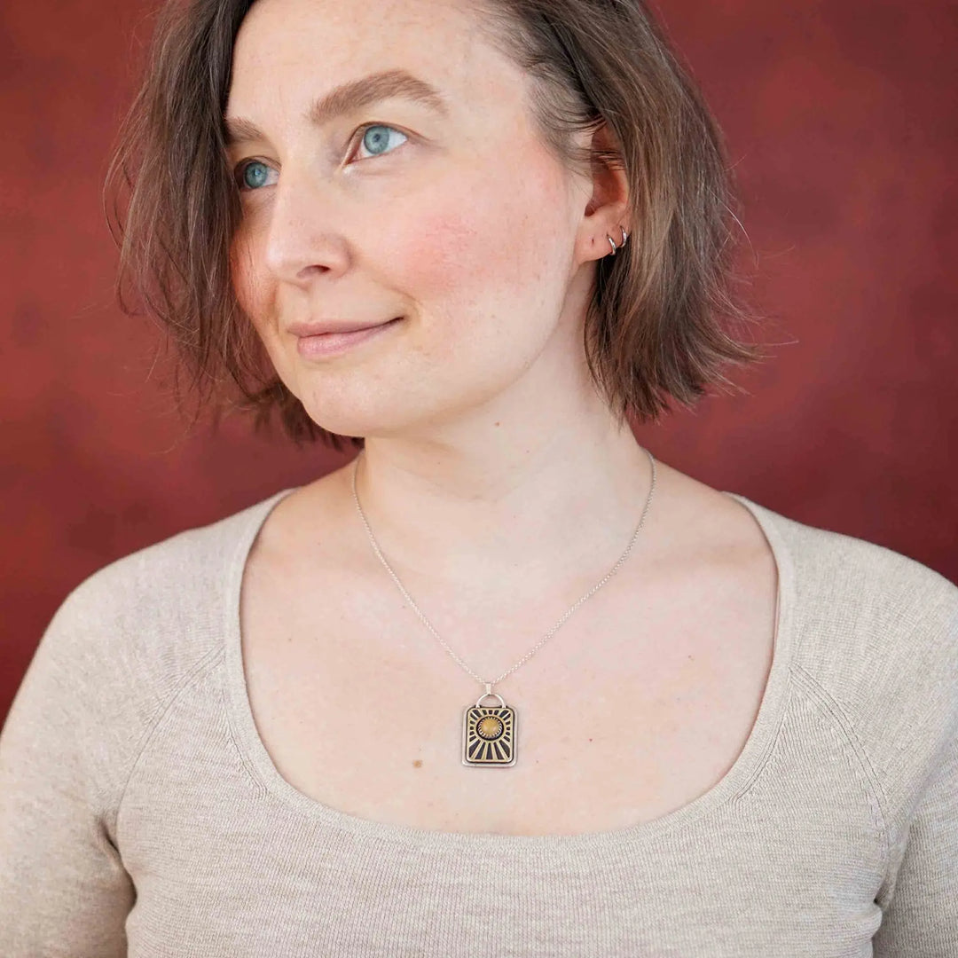 Kette aus Sterling Silber 925 mit gelbem Achat. Die handgefertigte Silberkette ist rechteckig und mit einer goldenen Sonne aus Messing versehen. In der Mitte der Sonne sitzt eingefasst in silberne Spitze, ein gelber Achat (Aventurin).
Auf der Rückseite des handgefertigten Sonnenanhängers ist zur Motivation eingraviert: "Alles unter der Sonne", um uns auch in schweren Zeiten zu erinnern, wie wertvoll das Leben ist.