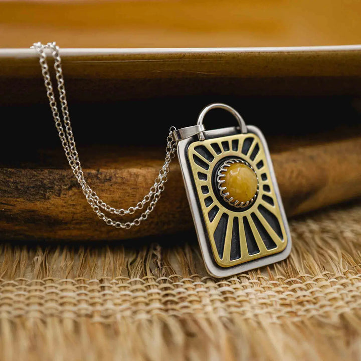 Kette aus Sterling Silber 925 mit gelbem Achat. Die handgefertigte Silberkette ist rechteckig und mit einer goldenen Sonne aus Messing versehen. In der Mitte der Sonne sitzt eingefasst in silberne Spitze, ein gelber Achat (Aventurin).
Auf der Rückseite des handgefertigten Silberschmucks ist zur Motivation eingraviert: "Alles unter der Sonne", um uns auch in schweren Zeiten zu erinnern, wie wertvoll das Leben ist.