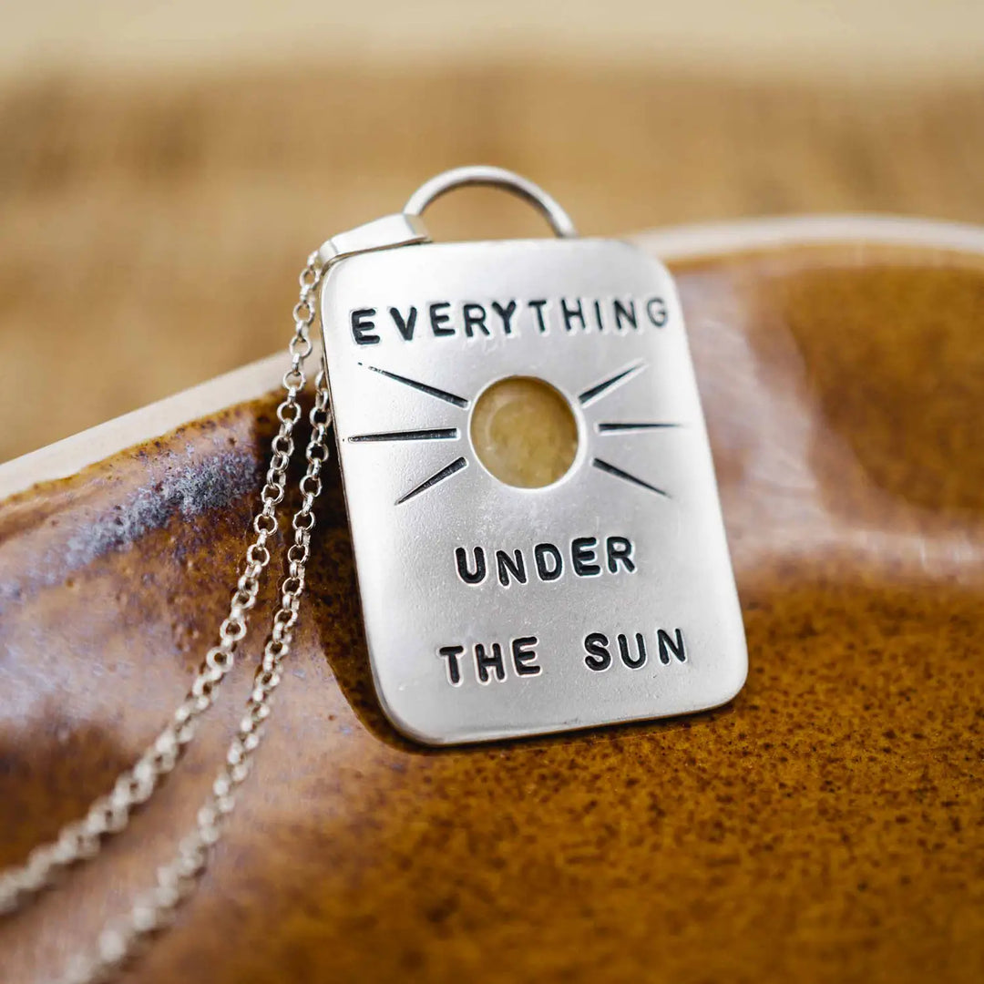Kette aus Sterling Silber 925 mit gelbem Achat. Die handgefertigte Silberkette ist rechteckig und mit einer goldenen Sonne aus Messing versehen. In der Mitte der Sonne sitzt eingefasst in silberne Spitze, ein gelber Achat (Aventurin).
Auf der Rückseite des handgefertigten Sonnenanhängers ist zur Motivation eingraviert: "Alles unter der Sonne", um uns auch in schweren Zeiten zu erinnern, wie wertvoll das Leben ist.