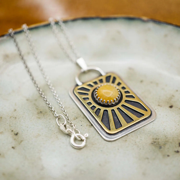 Kette aus Sterling Silber 925 mit gelbem Achat. Die handgefertigte Silberkette ist rechteckig und mit einer goldenen Sonne aus Messing versehen. In der Mitte der Sonne sitzt eingefasst in silberne Spitze, ein gelber Achat (Aventurin).
Auf der Rückseite des handgefertigten Sonnenanhängers ist zur Motivation eingraviert: "Alles unter der Sonne", um uns auch in schweren Zeiten zu erinnern, wie wertvoll das Leben ist.