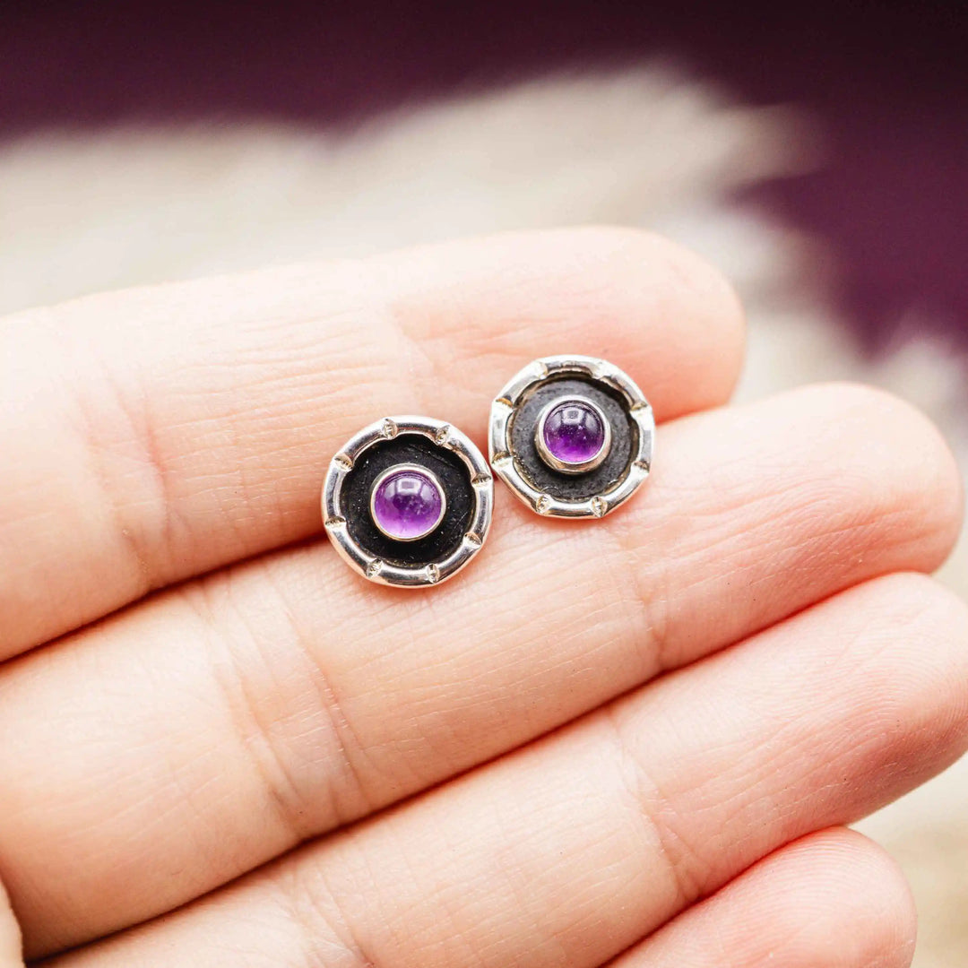 Kleine Ohrringe mit Stecker und natürlichem Amethyst auf einer Hand fotografiert
