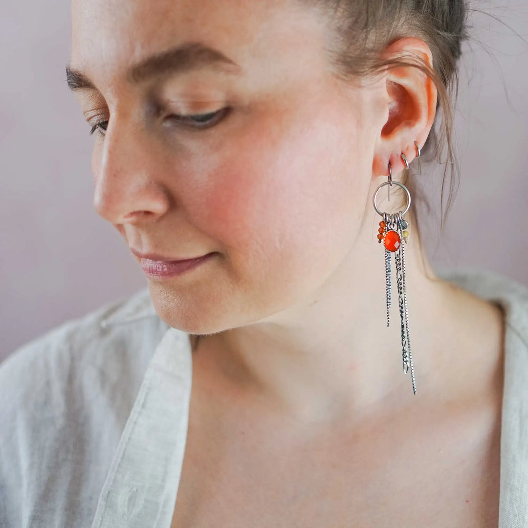 Lange Ohrringe aus Silber mit Quasten und Fransen aus Ketten. Die Ohrhänger tragen mehrere Edelstein Charms, unter anderem einen roten, facettierten Karneol.